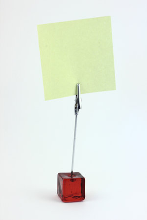 Red glass note-holder with alligator clip and blank yellow note - isolatedの写真素材