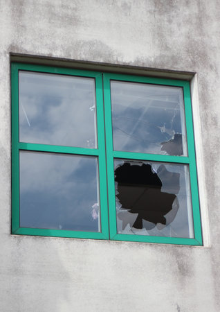 Broken glass in window with green frame at  factoryの写真素材