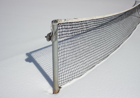 Tennis net at wintertime with snow and shadowの写真素材