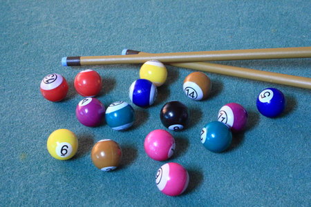 Pool balls on blue cloth in disorder with cues