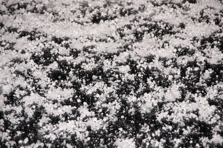 Cold white hail on a cars windshield