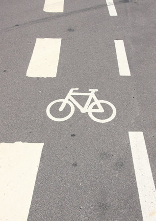 Vertical bicycle sign on asphalt with white stripes
