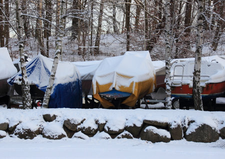 Sailing boats packed for the winter with snowの写真素材
