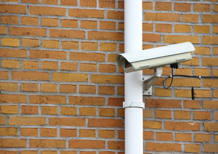 Surveillance Camera with Wire mounted on Yellow Brick Wallの写真素材