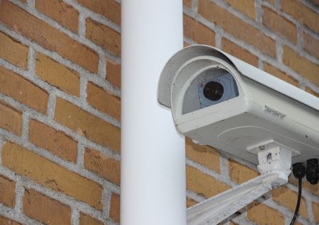 White Surveillance Camera Closeup mounted on Yellow Brick Wallの写真素材
