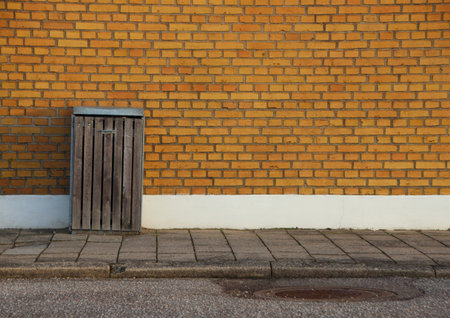 Wooden Outdoor Garbage Can with Yellow Brick Wall Backgroundの写真素材