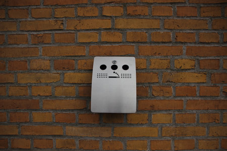 Outdoor Grey Steel Ashtray mounted on Yellow Brick Wallの写真素材