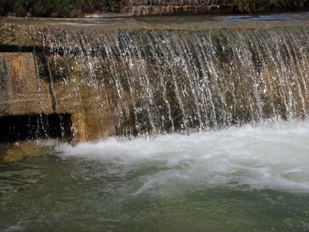 Waterfall in Drain Canal with Melting Water from Mountainsの写真素材