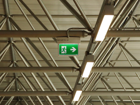 Green Emergency Exit Sign under Roof with Lampsの写真素材