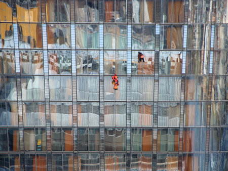 Two Window Construction Workers on Skyscraper with Colorful Reflectionの写真素材