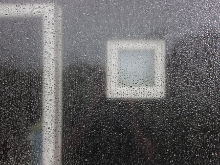Raindrops on Window Glass with Dark Black Wooden House Facade Background and Windowsの写真素材