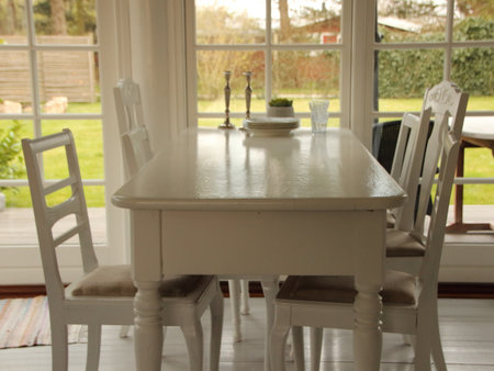 A classic dining room with a white table and four chairs. In the background you can see a backyard.の写真素材