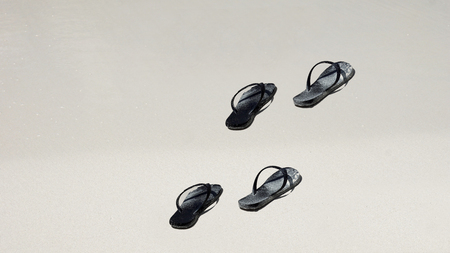 black slippers in white sand on tropical beachの写真素材