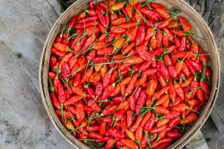 A wooden bowl filled with red chilis.