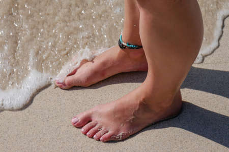 Barefooted woman on the beach waiting for the waves.