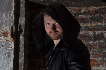Scary man with hood - photo of a man with brick bacgroundの写真素材