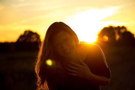 Beautiful teenager girl with glasses in the light of sunsetの写真素材