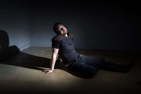 Photo of man sitting on the floor on dark background