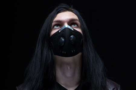 Portrait of the man with long hair in mask on black backgroundの写真素材