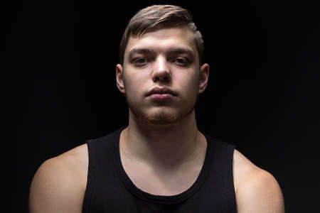 Portrait of the young strong man on black backgroundの写真素材
