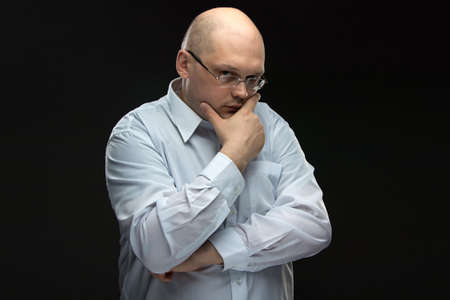 Photo of thinking man in glasses on black backgroundの写真素材