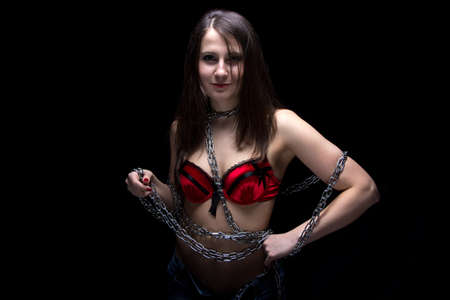 Photo of young woman in bra with chain on black backgroundの写真素材