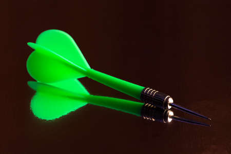 Photo of green dart and it reflection on black backgroundの写真素材