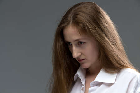 Photo of young woman with bowed head on grey の写真素材