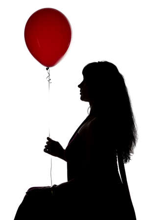 Photo of sitting womans silhouette with red balloon in profile on white backgroundの写真素材