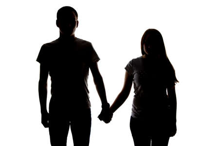 Silhouette of two teenagers holding hands on white backgroundの写真素材