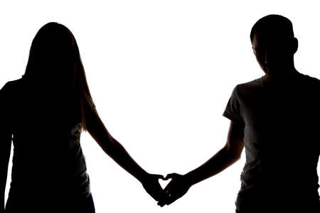Silhouette of two teenagers showing heart on white backgroundの写真素材