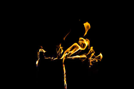 Photo of bright orange flame by night on black background