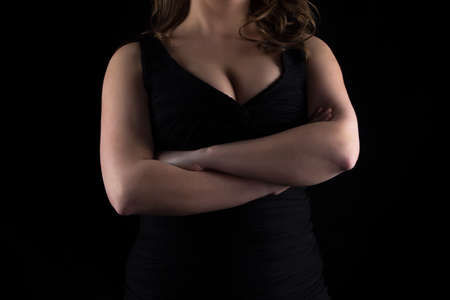 Photo of curvy woman's bust with arms crossed on black backgroundの写真素材