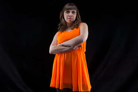 Image of pudgy woman with arms crossed on black backgroundの写真素材