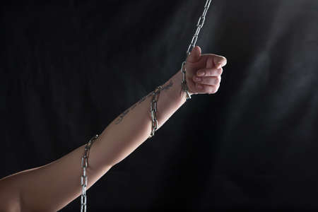 Photo of woman's hand with chain on black background