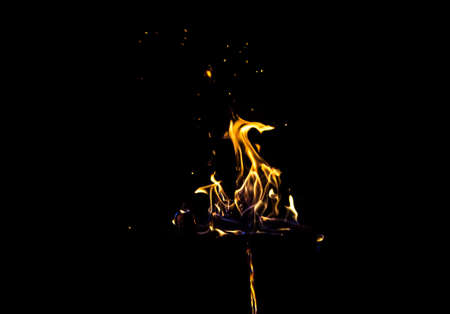 Image of bright orange flame by night on black background