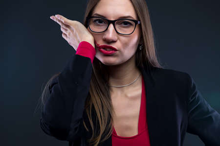 Image of woman smudging lipstick on black background