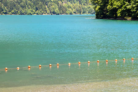 Photo of a clean mountain lake with buoys in the summer