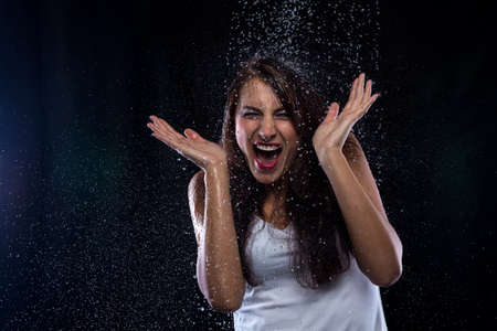 Young brunette and drops of water on black backgroundの写真素材
