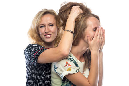 Two joking fun sisters on white background