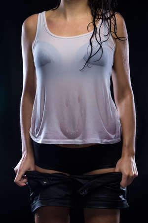 Undressing shorts wet woman on black background