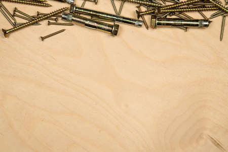 Golden screws on top with wood background. Photo of construction background.の写真素材