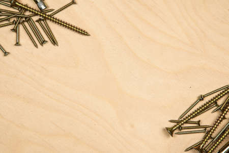 Gold screws diagonally with wood background. Photo of construction background.の写真素材