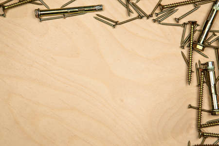 Gold screws on top and right with wood background. Photo of construction background.の写真素材
