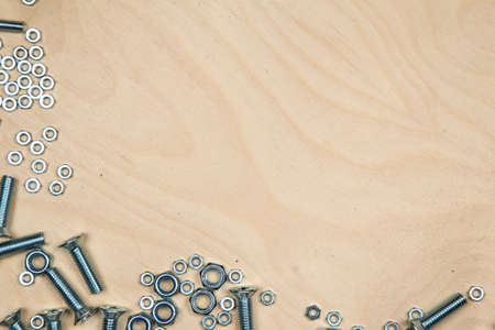 Boltas and nuts on bottom left with wood background. Photo of construction background.の写真素材