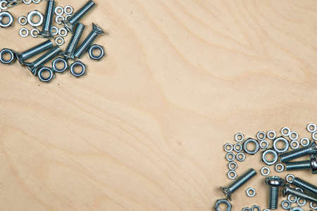 Boltas and nuts on diagonal with wood background. Photo of construction background.の写真素材