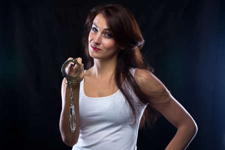 Woman with handcuffs in hand. Portrait photo with black background.の写真素材