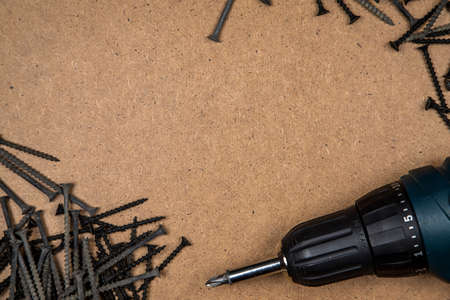 Screwdriver and screws on the wood plate. Construction background with tools.