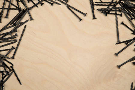 Screws on top left and right of wood plate. Construction background with tools.