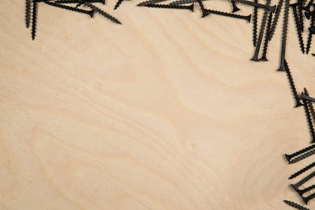 Screws on top and right of wood plate. Construction background with tools.の写真素材